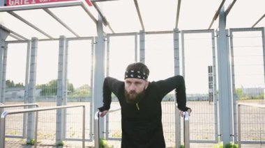 Spor giysileri içinde, stadyumun giriş kapılarının demir parmaklıklarına tırmanan yakışıklı, konsantre ve güçlü sakallı adama yakın durun.