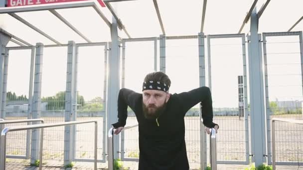 Крупним планом красивий концентрований активний бородатий чоловік у спортивному одязі, який штовхає залізні поручні вхідних воріт стадіону — стокове відео