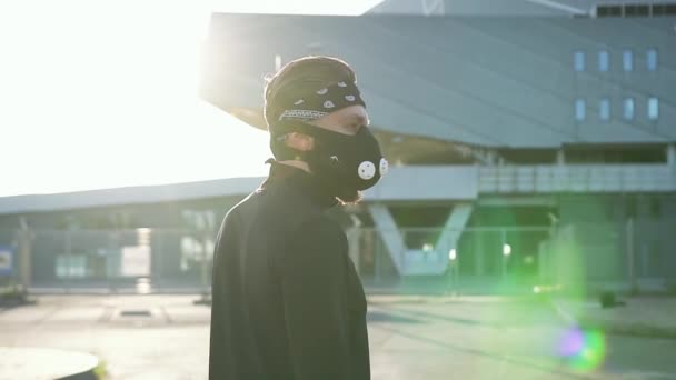 Zijaanzicht van sympathieke sportieve geconcentreerde jonge bebaarde atleet in sportkleding in beschermende masker die voor de grote stad stadion staan — Stockvideo