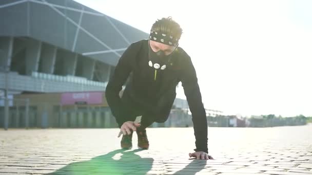 Front view of attractive active strong bearded man in mask and sportswear which doing push-ups with clapping hands during outdoors workout on stadium — Stock Video