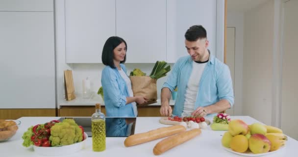 가족과 함께 저녁 식사를 준비하기 위해 현대 요리에 매혹적으로 미소짓는 행복 한 부부 — 비디오