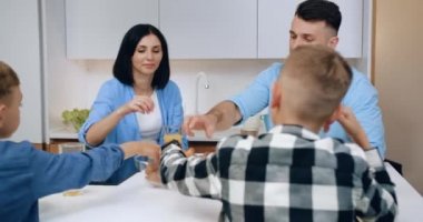 Güzel, mutlu, güler yüzlü aile sabah kahvaltısını kruvasan ve meyve suyuyla yapıyor.