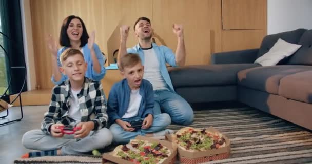 Atraktivní portrét dobré temperamentní šťastné spokojené rodiny, která slaví vítězství ve videohře a zvedl ruce a dává vysoké pět — Stock video