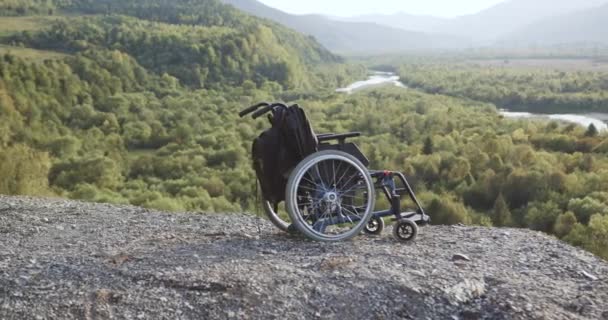 아침아름다운 자연 속 언덕 위에 누워 있는 책가방으로 의료용 휠체어를 클로즈업 — 비디오