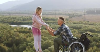 Güzel görünüşlü mutlu bir çiftin portresi. Engelli bir adamın karısıyla birlikte tekerlekli sandalyeden kalkması ve hastalıktan sonra ilk adımlarını atması.