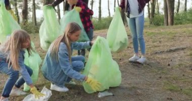 İyi görünümlü, çalışkan doğa eylemcilerinin yan görünüşü. Birlikte çöpleri parktaki plastik torbalara dolduruyorlar. Böylece doğayı güzellik ve saflıkta koruyorlar.