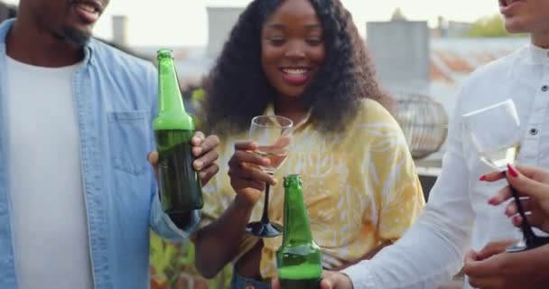Probable insouciant sympathique multiethnique jeune clinquant bouteille de bière et de verres avec du vin lors de la fête des amis sur la terrasse donnant sur les toits de la ville — Video