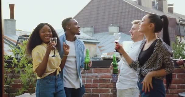 Крупним планом усміхнені задоволені молоді багаторасові групи людей, які святкують вечірку друзів на балконі з запальними танцями — стокове відео