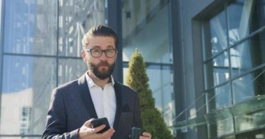 Çekici, kendine güvenen, yetişkin, sakallı ofis müdürünü kapatın. Kahve molası verip cep telefonunu kullanıyor.