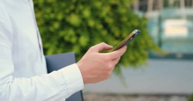 Akıllı telefon kullanan ve dizüstü bilgisayar tutan erkeklerin yan görüntüsü. Akıllı telefon ekranında parmaklarının çevirdiği numara. Açık havada. Yavaş çekim