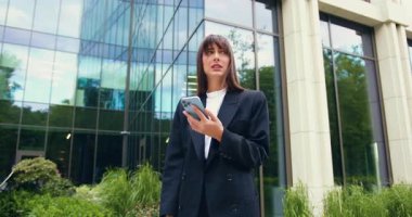 Kafkasyalı genç bir kadın elinde akıllı bir telefonla kötü haberler okuyor ya da açık havada ticari bir binanın önünde dururken cep telefonu uygulamasından hayal kırıklığına uğruyor. Yavaş çekim