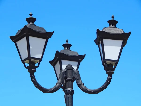 black street lamp in an open blue sky.