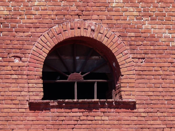 antique window lined with red brick wall.
