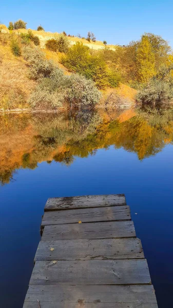 Banco de rio paisagem com árvores verdes amarelas em um dia de verão refletido na água — Fotografia de Stock