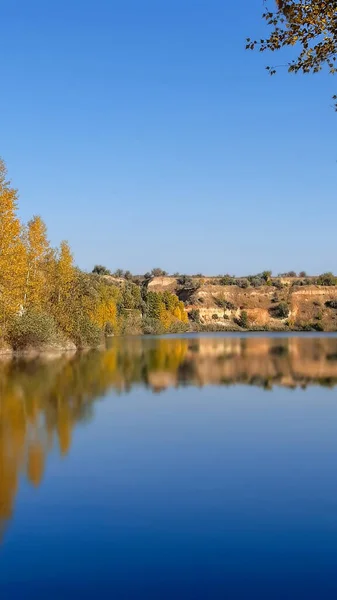 Banco de rio paisagem com árvores verdes amarelas em um dia de verão refletido na água — Fotografia de Stock