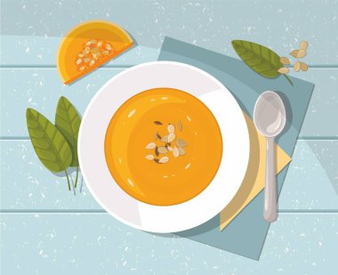 Pumpkin soup with spoon on blue  background. Top view. clipart