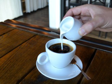 Beyaz ahşap bir masa üzerinde siyah kahve fincan. yanındaki Kupası ver. Cafe iş kavramı. kahve. uçan daire ile el Kupası. reklam için kullanılabilir. metin için yer