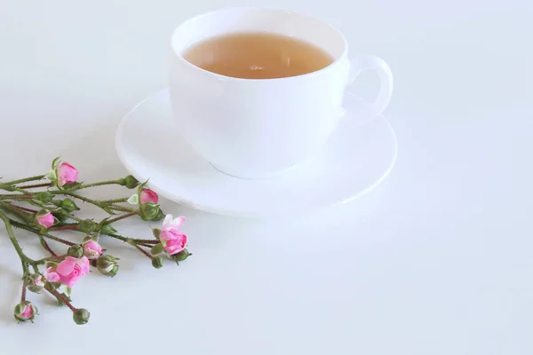 Florale Komposition aus schönen rosa Rosen auf weißem Holzgrund mit einer Tasse Tee. Weiblicher Bürotisch, gestyltes Aktienbild, flache Lage, Draufsicht. Leerraum für Ihren Text. — Stockfoto