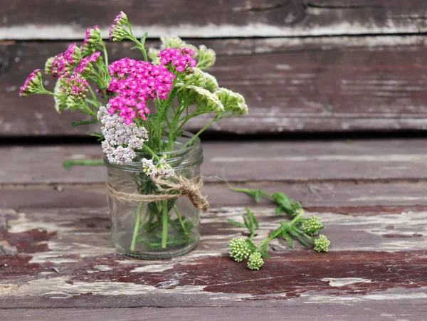 Vetro con fiori achillea millefolium, comunemente noto come achillea o achillea comune su tavole di legno rustico intemperie. Pianta medicamentosa.Spazio vuoto per il testo . — Foto Stock