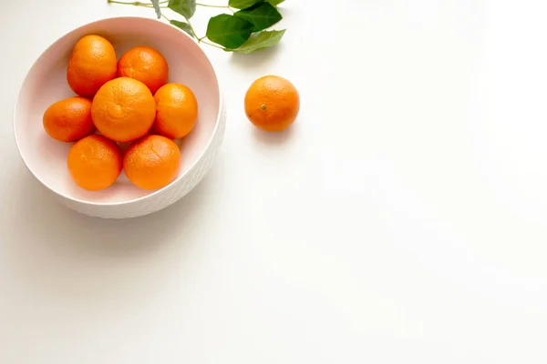 White china bowl filled with juicy fresh mandarins on white background. Fresh organic mandarins fruit for healthy life and detox snacks. Picture design for foods background. Top view. — Stock Photo, Image