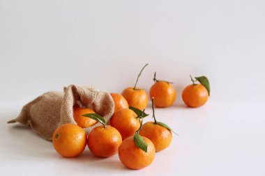 Beyaz ahşap masa üzerinde çanta içinde yeşil yaprakları ile taze ham organik mandalina. Uzay kopyalayın. Zengin gıdalar arka plan için besinler, lif ve vitamin, resim tasarım.