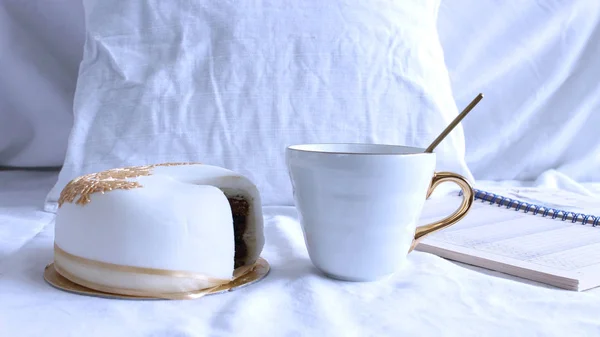Gezellige winterochtend Ontbijt op bed stilleven scène. Dampende kopje warme koffie, thee en lekkere taart. Kerst concept. Kussens en een notebook . — Stockfoto
