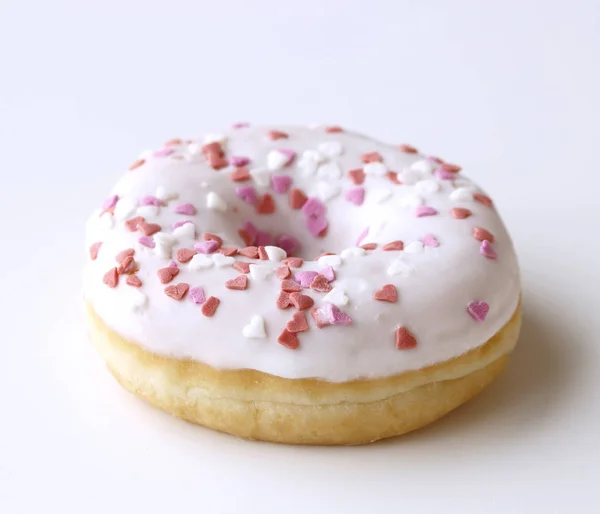 Donut blanco con aspersiones sobre una mesa de madera blanca. Estilo retro. Concepto de desayuno Detalle de la comida. De cerca. Color pastel . — Foto de Stock