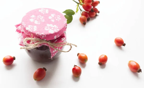 Tarro de vidrio de mermelada de rosa mosqueta casera con jugosas frutas frescas en forma de ingredientes, aislado sobre fondo blanco. Deliciosa fruta. Fondo borroso.Alimentación y concepto saludable . — Foto de Stock