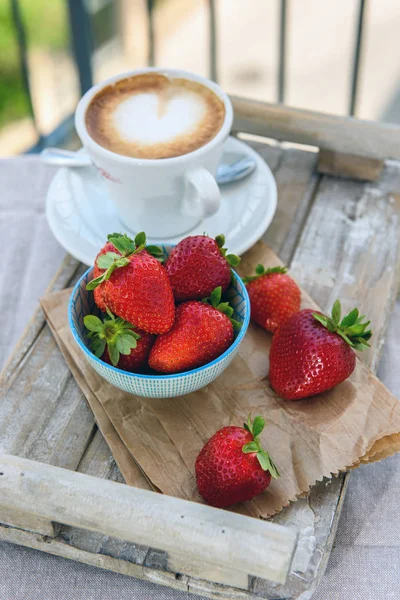 Taze çilek ve bir fincan kahve bir ahşap tepsi içinde. Seçici odak.