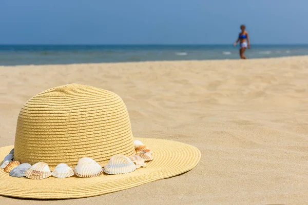 Hat from the sun on the sand, sea shells, sea. The concept of a beach holiday. Copy space.