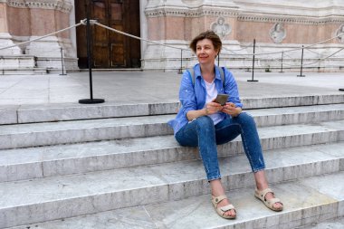 İnce, ince orta yaşlı bir kadın, Bologna, İtalya için turist. Şehir Merkezi Meydanı'nda San Petronio Bazilikası adımlardan oturur. Avrupa'ya seyahat.