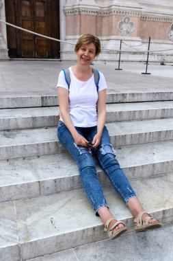  İnce, ince orta yaşlı bir kadın, Bologna, İtalya için turist. Yorgun, katedrali merdivenlerinde oturmuş. Avrupa'ya seyahat.
