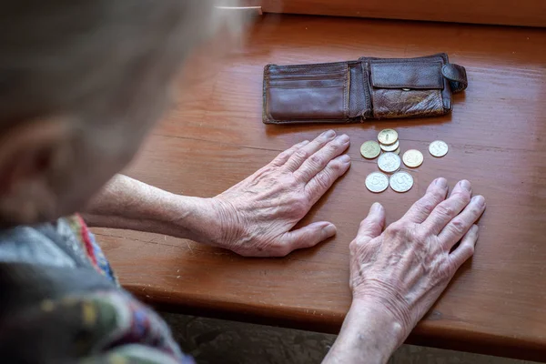 Hands of an elderly woman counting money. The concept of poverty, austerity, saving money.