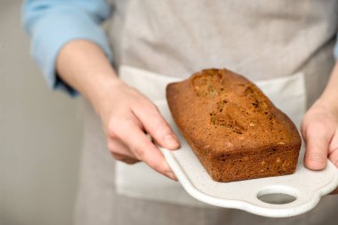 Kadınların elleri taze pişmiş ekmek keklerini tahıl ve tohumlarla tutuyor. Ev yapımı kekler seramik bir tahtada servis edilir..