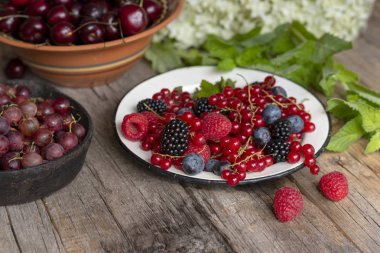 Kaba bir ahşap masa üzerinde kaselerde Çilek. Yaz meyveleri çeşitli.