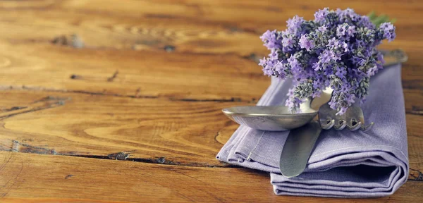 Cutlery, lavender and napkin on a wooden background