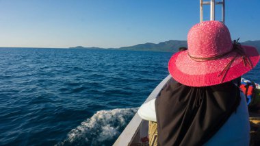 kadınlar peçe ve açık mavi karanlık deniz ve ada mesafe karimun jawa Endonezya ile teknenin şapka