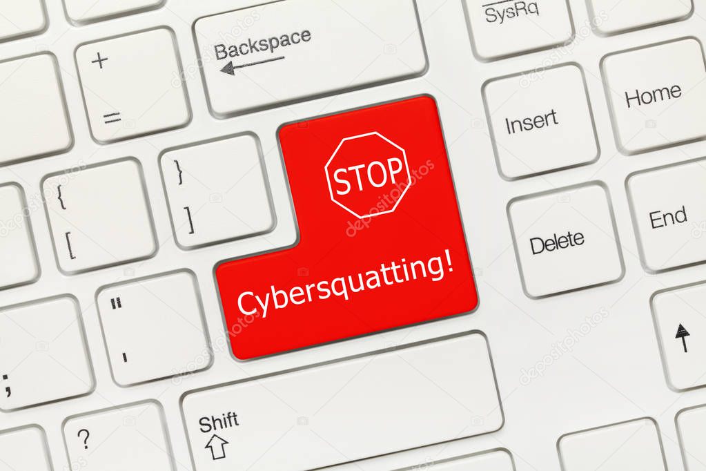 Close-up view on white conceptual keyboard - Cybersquatting (red key with STOP sign)