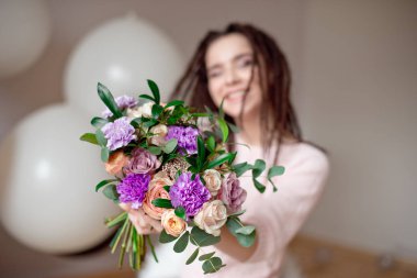 Bir buket çiçek elinde kapalı gösterilen dreadlocks saç modeli ile gülümseyen kız. Arka plan üzerinde bulanık kızla çiçekler üzerinde odaklanmak.