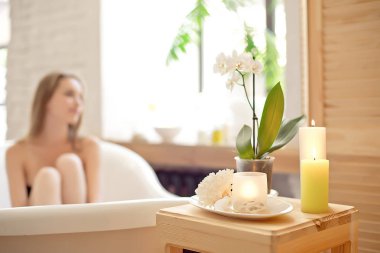 Mumlar ve arka plan üzerinde bulanık kadınla spa salonda ahşap masaya çiçek