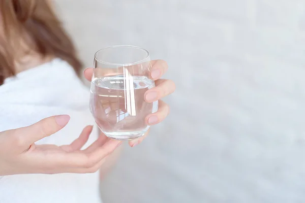 Yakın çekim beyaz bir gülümseyen kadın spa sonra bir bardak su tutan beyaz havlu ile kaplı.