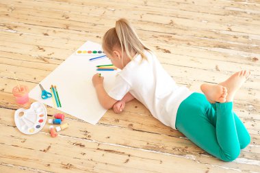 yere yat döşeme ve büyük beyaz kağıt üzerine resim okul öncesi güzel kız