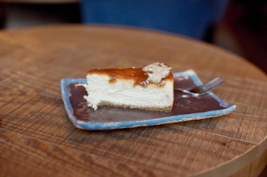 plaka üzerinde ahşap masa, lezzetli kremalı pastadan dilim ile yakın çekim