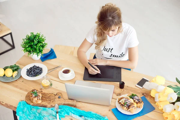 Jonge aantrekkelijke vrouw freelancer vergadering front laptopcomputer puttend uit grafisch tablet, zakenvrouw zitten aan de tafel met een kopje koffie. — Stockfoto