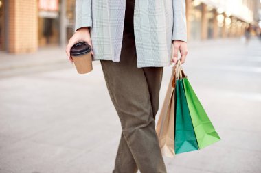 Yakın çekim Genç moda kadın alışveriş ayakta açık havada sokakta vitrin vitrinler yakınındaki torbaları ile.