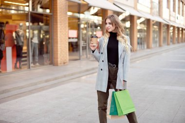 Sevimli genç moda kadın alışveriş ayakta açık havada sokakta vitrin vitrinler yakınındaki torbaları ile.