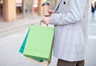 Yakın çekim Genç moda kadın alışveriş ayakta açık havada sokakta vitrin vitrinler yakınındaki torbaları ile.