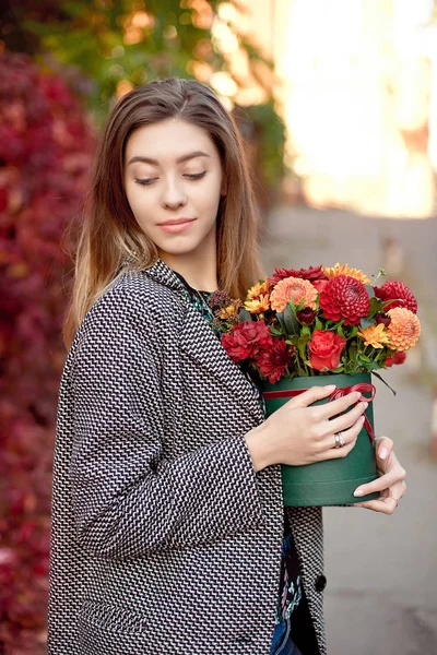 Кавказская модная женщина, стоящая на улице возле витрин магазина с цветочной коробкой и счастливой улыбкой — стоковое фото