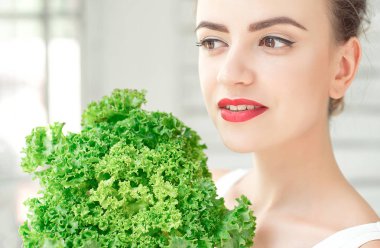 Gülümseyen genç kadın tutarak marul yaprakları