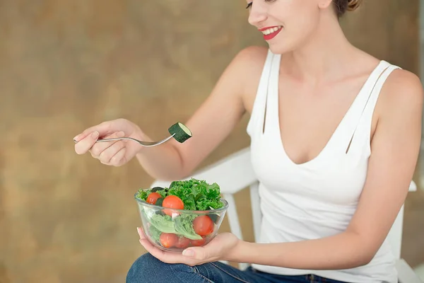 Крупним планом жінка ззаду тримає миску свіжого овочевого салату, тримаючи виделку в руці . — стокове фото